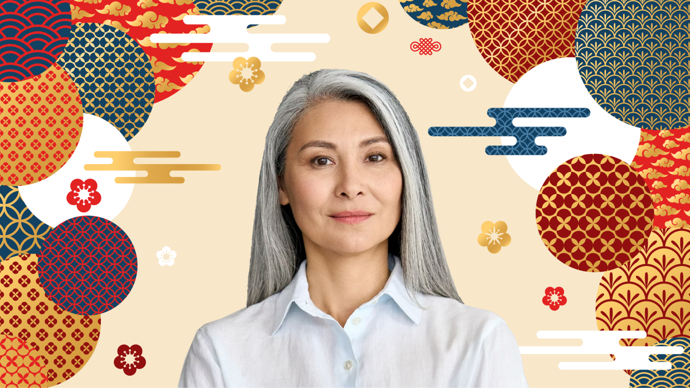 person with long gray hair standing in front of background with circles with teal, burgundy, gold, red Asian prints